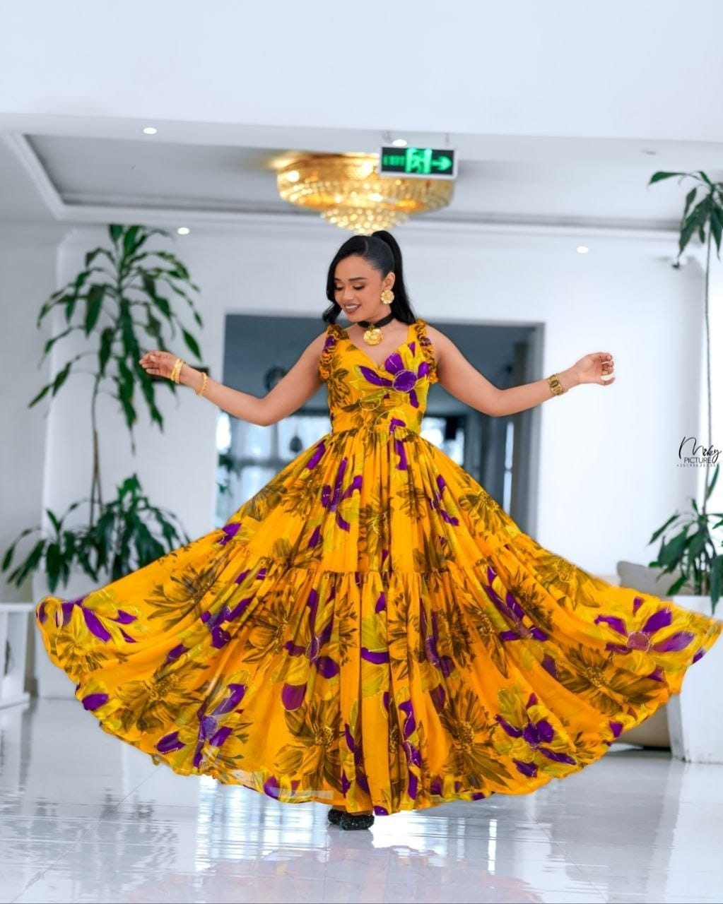 Woman wearing a flowing yellow and purple floral 9F gown